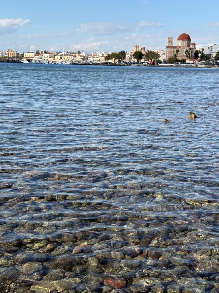 Costa de Egina con aguas transparentes y el puerto al fondo